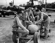 Asisbiz RNZAF 31 Servicing Unit Corsairs with pilots gathered around a bomb trolley to discuss a strike 01