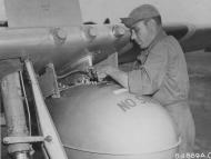 Asisbiz P 51D Mustang 7AF 21FG46FS SSGT Russel A Skaggs attaches a 100 gallon drop tank at Iwo Jima 1945 01