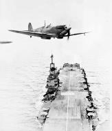 Asisbiz Fleet Air Arm Seafire flies over its carrier 01